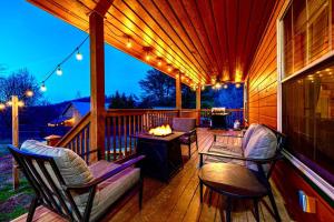 a porch with two chairs and a table with a fire at One Level, Pet Friendly, Huge Fenced in Yard, Views, EasyRoads, Pool Table, Spa, Theater, Outdoor fun in Sevierville