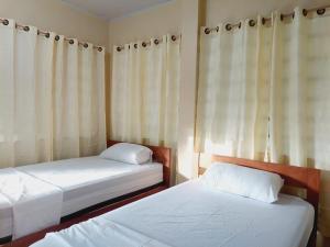 2 Betten in einem kleinen Zimmer mit Vorhängen in der Unterkunft Hostal Beru in Puerto Nariño