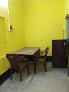 uma mesa e duas cadeiras num quarto com uma parede amarela em SPG HOLIDAY em kolkata