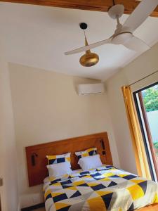 a bedroom with a bed and a ceiling fan at Le havre des salines - Villa palétuvier in Bourda