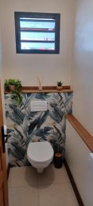 a bathroom with a toilet with a tropical wallpaper at Le havre des salines - Villa palétuvier in Bourda