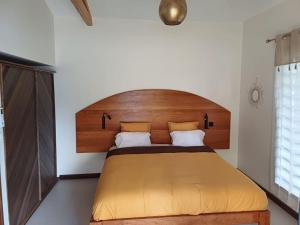 a bedroom with a large bed with a wooden headboard at Le havre des salines - Villa palétuvier in Bourda