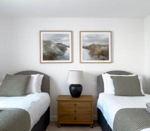 a bedroom with two beds and a table with a lamp at Salters Cottage - Stunning Modernised 3 BR Home Just Steps From the Beach in Budleigh Salterton