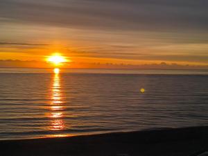 a sunset over the ocean with the sun setting at Appartement de vacances - Splendide vue sur mer, Parking privé in Le Barcarès