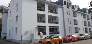 deux voitures garées devant un bâtiment blanc dans l'établissement Ferienwohnung Dreiländereck 1, à Lörrach