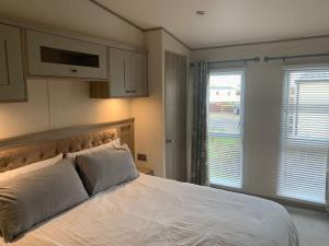 a bedroom with a large white bed and a window at Unwind@13 Badger Lakes, Haggerston, Northumberland in Beal