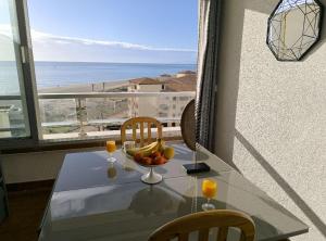 a table with a bowl of fruit and a view of the ocean at Appartement de vacances - Splendide vue sur mer, Parking privé in Le Barcarès