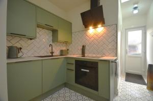 a kitchen with green cabinets and a stove at The Gate Lodge in Helensburgh
