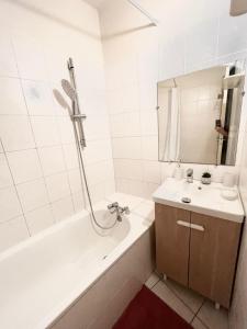 een witte badkamer met een bad en een wastafel bij Charme et Confort in Villeneuve-lès-Béziers
