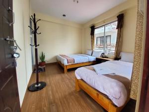 a hotel room with two beds and a window at santoshi guest house in Pokhara