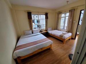 um quarto com 2 camas e 2 janelas em santoshi guest house em Pokhara