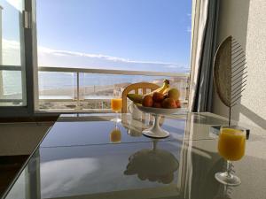 a table with a bowl of fruit and two glasses of orange juice at Appartement de vacances - Splendide vue sur mer, Parking privé in Le Barcarès