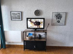 a tv on a stand in a room with a wall at Appartement de vacances - Splendide vue sur mer, Parking privé in Le Barcarès