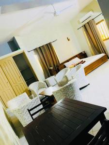 sala de estar con sillas, mesa y cama en AULNES RESIDENCE HOTEL en Cotonú