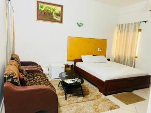 ein Schlafzimmer mit einem Bett und einem Sofa in der Unterkunft AULNES RESIDENCE HOTEL in Cotonou