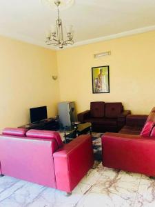 una sala de estar con 2 sofás rojos y un sofá en AULNES RESIDENCE HOTEL, en Cotonou