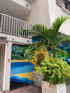 un mural en el lateral de un edificio con una palmera en Le Tournesol, en La Saline-Les-Bains