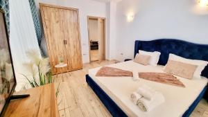 a bedroom with a large bed with a blue headboard at KYD VILA - Studiouri si Apartamente la 100m de Plaja Debarcader in Eforie Nord