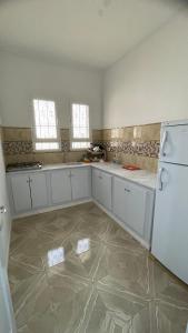 a large kitchen with white cabinets and a refrigerator at Dar elrayen in Tozeur