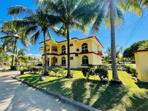 una casa amarilla con palmeras delante en Honduras Shores Plantations, en Tela