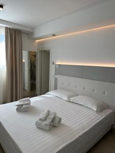 una camera da letto con un grande letto bianco con asciugamani di Amani Chic Rooms a Olbia