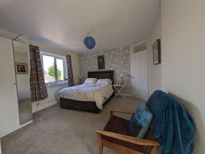 a bedroom with a bed and a chair and a window at Pool Farm in Redditch