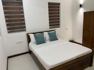 a bedroom with a bed with two blue pillows at Silina Airport Residence in Katunayake