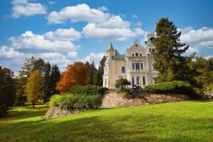 an old mansion on a grassy hill with trees at Hotel Château Cihelny in Karlovy Vary