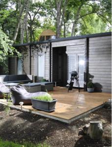 a house with a wooden deck with a grill at Lodge-Altjeßnitz-Goitzsche 