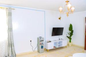 een woonkamer met een televisie en een witte kast bij jenna stays in Nyeri