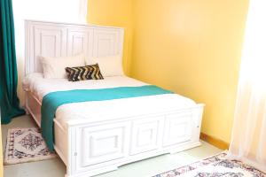 een wit bed in een kamer met gele muren bij jenna stays in Nyeri