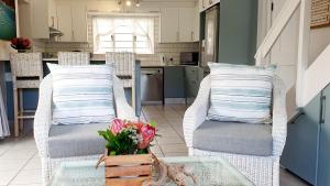 a kitchen with two chairs and a table with a vase of flowers at Cozy Island Living at The Grove cottage in Knysna +23 photos