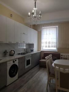 uma cozinha com armários brancos, uma mesa e uma sala de jantar em Lux Apart em Chisinau
