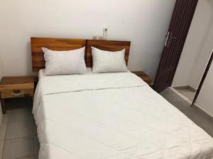 um quarto com uma cama grande com lençóis brancos e almofadas em Résidences Touristhotel em Abidjan