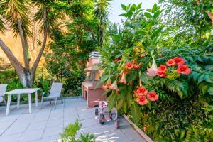 un giardino con fiori rossi e tavolo e sedie di Almyra Apartments & Studios ad Agios Gordios