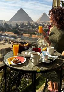 Unique Pyramids View INN في القاهرة: امرأة تجلس على طاولة مع الطعام والمشروبات