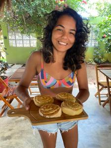 Eine Frau im Bikini mit einem Tablett Brot. in der Unterkunft Pousada Águas de Tamandaré in Tamandaré