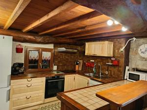 a kitchen with wooden cabinets and a sink at Grange ancienne aménagée in Rabat-les-Trois-Seigneurs