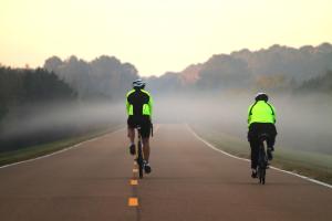two people riding bikes down a road in the fog at America Best Value Inn Kosciusko in Kosciusko