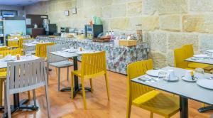 a dining room with tables and yellow chairs at Hotel Junquera in Vigo