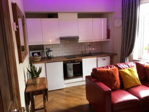 una cucina con armadi bianchi e un divano rosso di Top O’ Th’ House . Hebden Bridge a Hebden Bridge