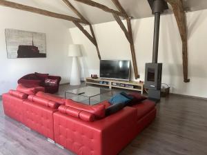 een rode bank in een woonkamer met een tv bij Gite de Bervic, hebergement de caractere in La Capelle-Balaguier