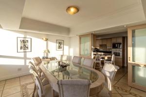 a living room with a glass table and chairs at Beachfront Seaview in Cape Town