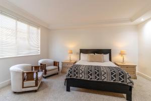 a bedroom with a bed and two chairs at Beachfront Seaview in Cape Town