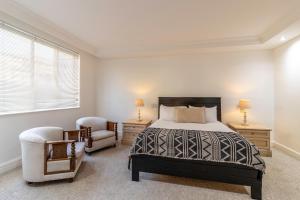 a bedroom with a bed and two chairs at Beachfront Lifestyle in Cape Town