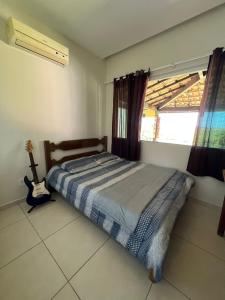 ein Schlafzimmer mit einem Bett und einem Fenster mit einer Gitarre in der Unterkunft Casa no Sítio - Vovó Lalá in Cabo Frio
