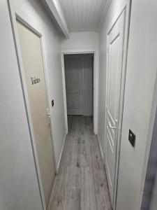 een lege hal met twee witte deuren en een houten vloer bij Appartement meublé , 1 chambre in Magnanville