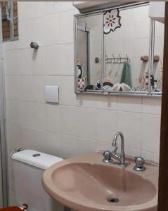 a bathroom with a sink and a toilet and a mirror at FrenteMar OuroVerde BetoCarrero in Navegantes