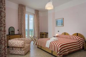 a bedroom with two beds and a chair and a window at Hotel Marcelli in Numana