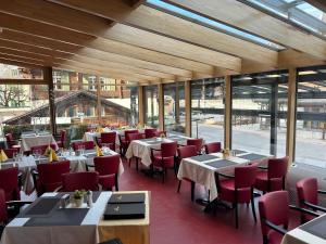 a restaurant with tables and red chairs and windows at Post Hotel Vista in Zweisimmen